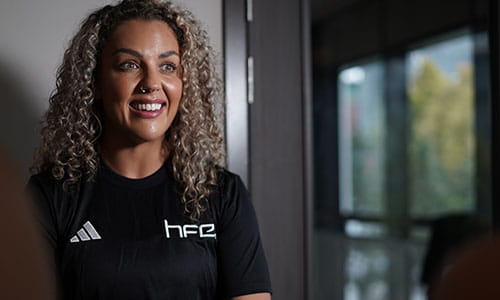 A female fitness professional wearing a HFE top and smiling