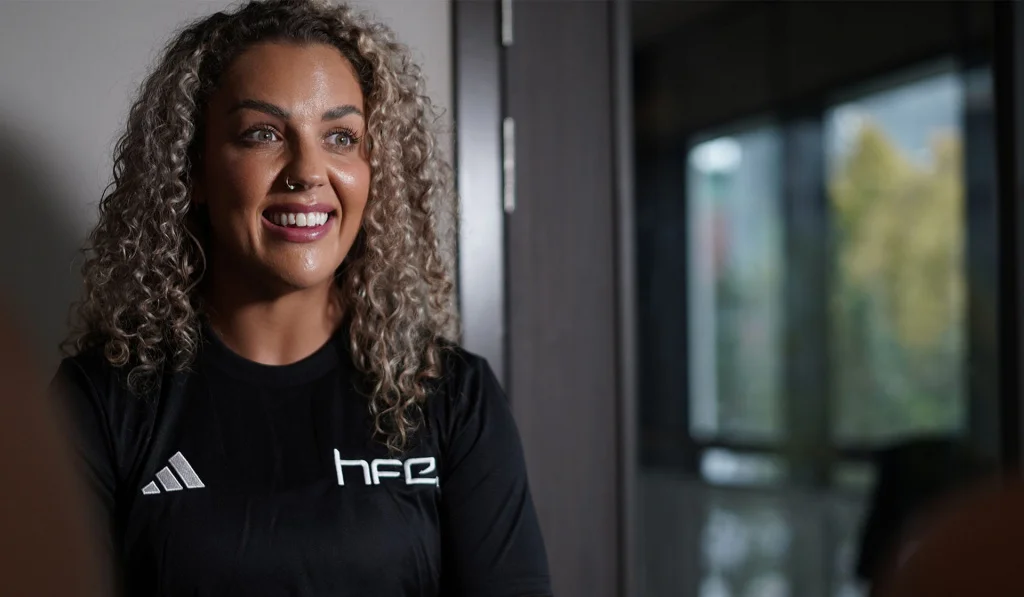 A female fitness professional wearing a HFE top and smiling