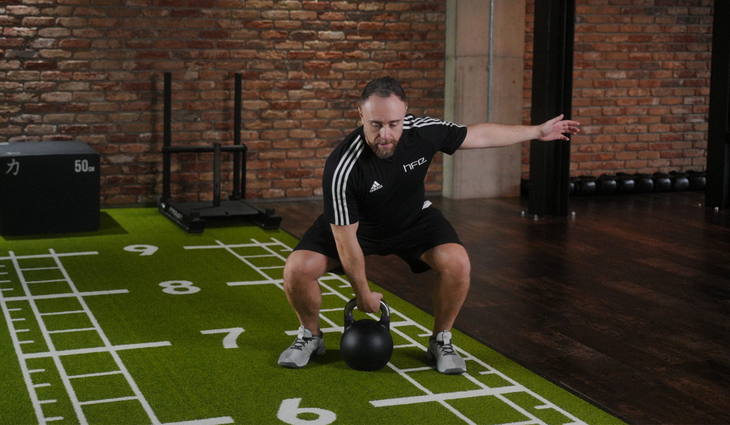 A personal trainer demonstrating how to use a kettlebell