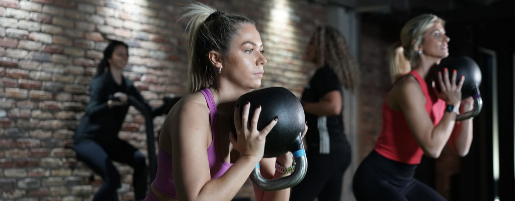 A group of females training in a gym using kettlebells A group of females training in a gym using kettlebells