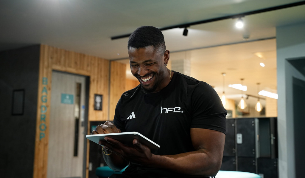 A male personal trainer in a gym working on a tablet A male personal trainer in a gym working on a tablet