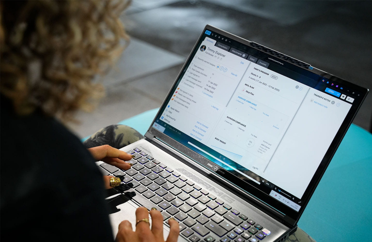 A fitness professional sat working on a laptop