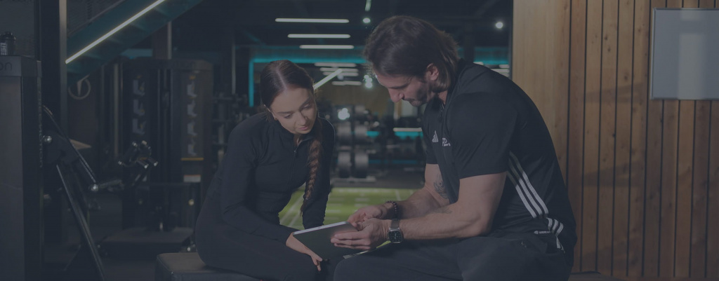 A male PT sat with a female client completing a form