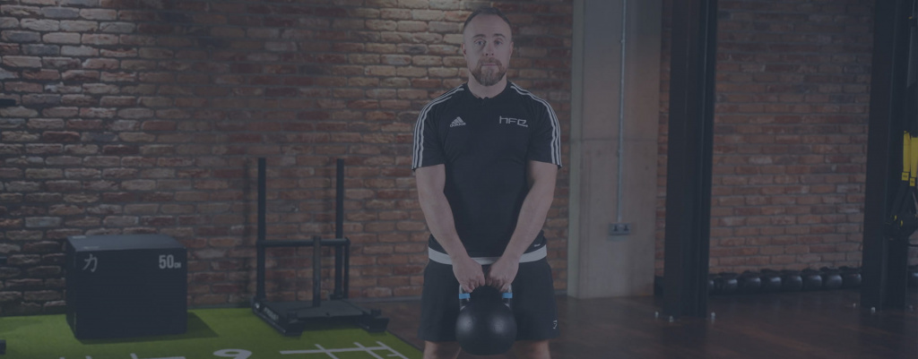A male PT in a gym lifting a kettlebell