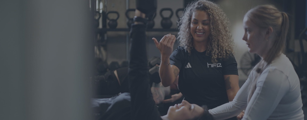 A female PT guiding a PT student helping a client A female PT guiding a PT student helping a client