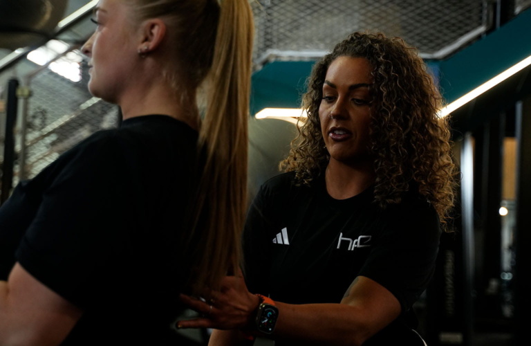 A female PT supporting a client in the gym