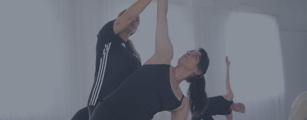 A fitness instructor helping a female client perform a yoga exercise A fitness instructor helping a female client perform a yoga exercise