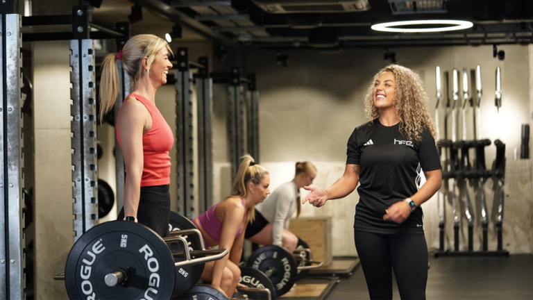 A PT supporting a group of women in a gym