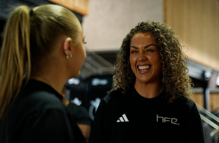 A female PT stood with a female in a gym while laughing