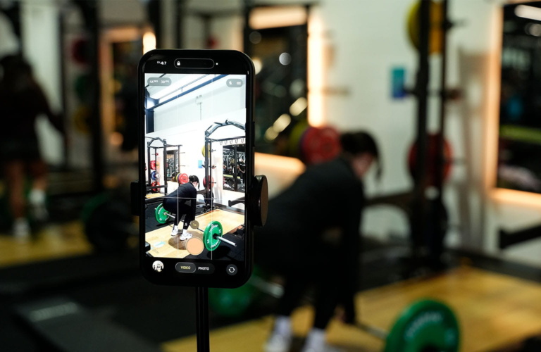 A female in a gym recording her workout on her phone