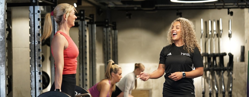 Woman in the gym with her personal trainer performing the deadlift Woman in the gym with her personal trainer performing the deadlift