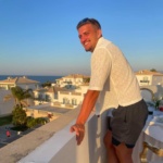 Louie John Spencer Callegari standing on a balcony smiling at the camera