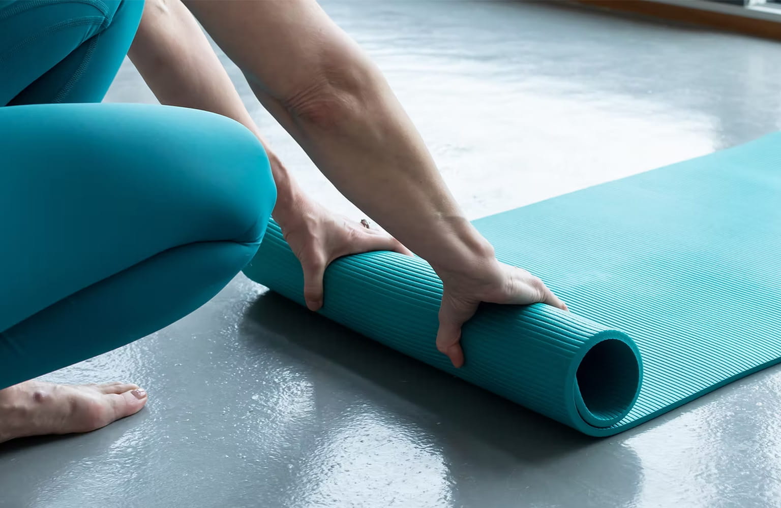 Someone rolling up a Pilates mat