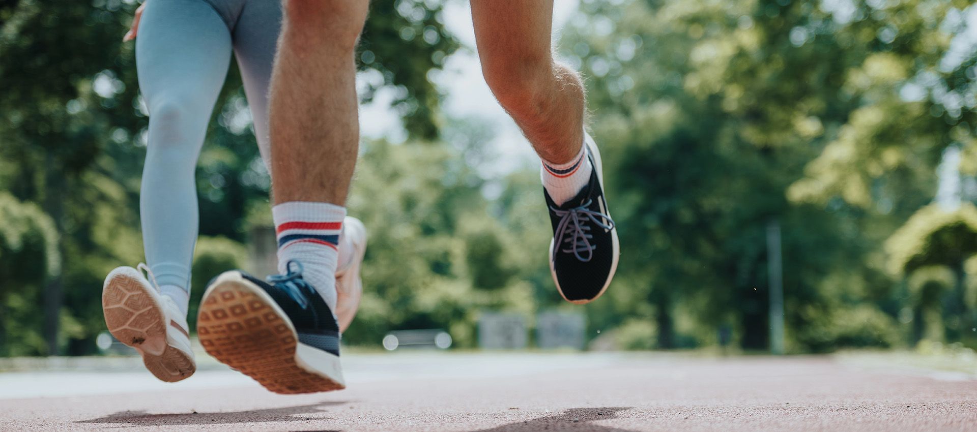 Close-up of two people running and their footwear